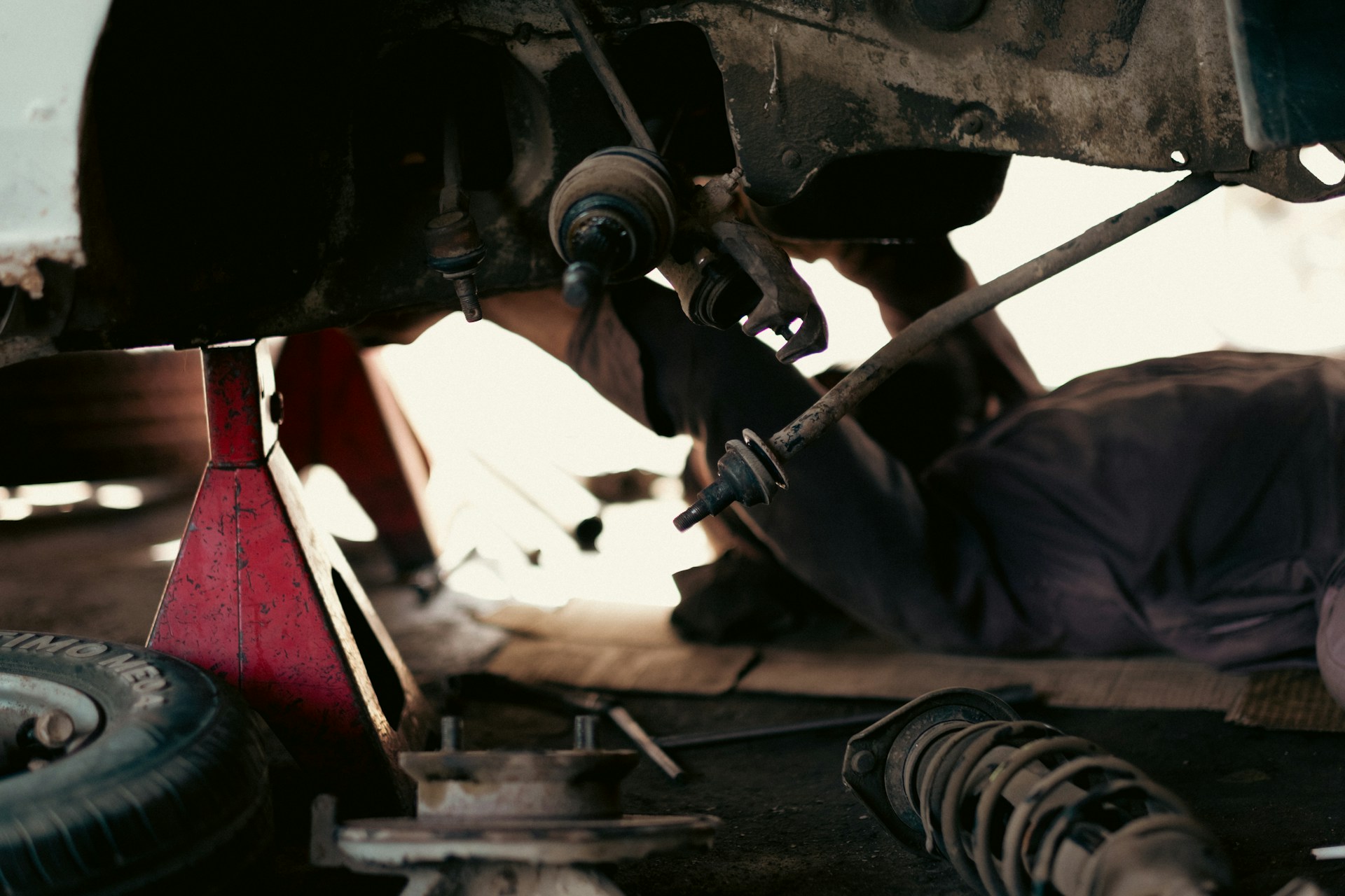 A man working on a car under a vehicle